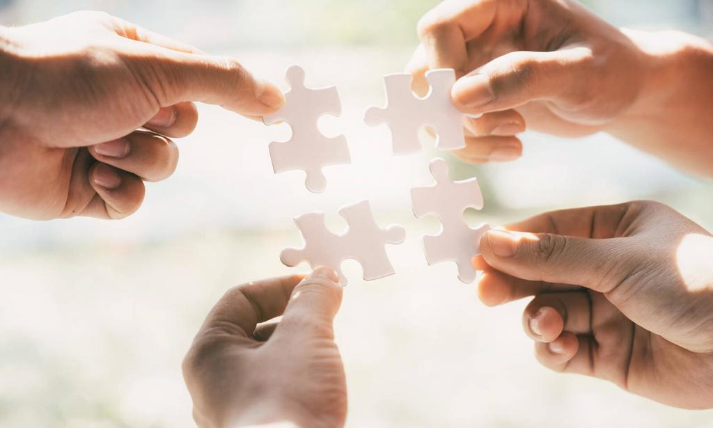 Hände halten Puzzle Teile zusammen